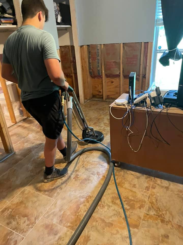 Workers cleaning up tile floors after removing wall materials on water restoration job - Quillen Construction Group