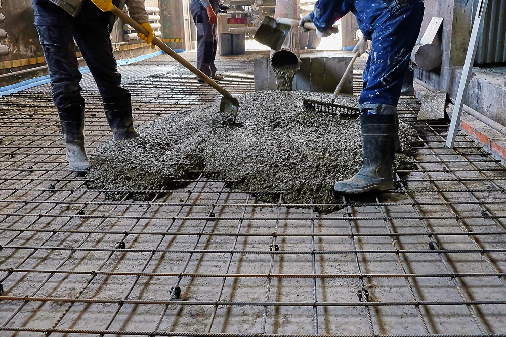 Workers moving fresh concrete into place as its poured from the mixing truck on site.