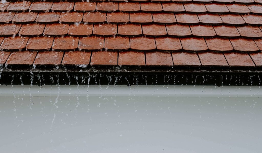 Image of rain falling off roof tiles.