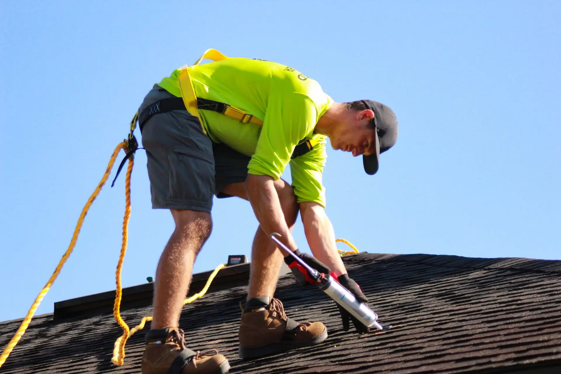 A picture of a man in a high-visibility shirt on a roof with caulk