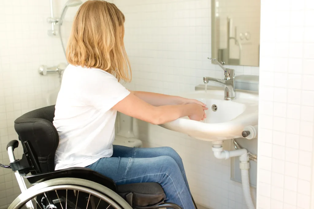 A picture of a girl in a wheelchair washing her hands in an ADA-compliant, low-height sink for the blog "The Guide to ADA Compliant Bathroom Remodels in New Orleans".