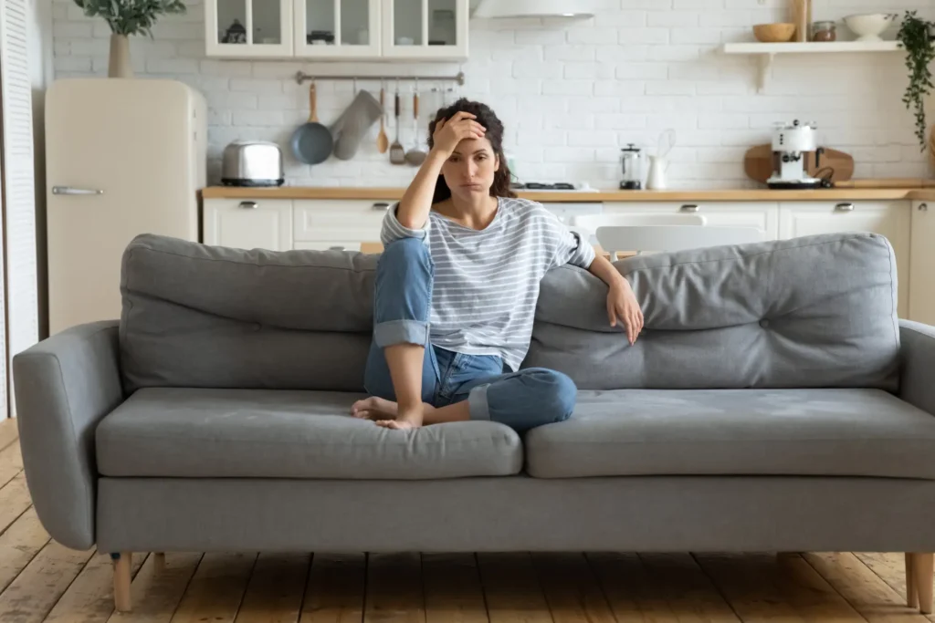 How to Survive a Kitchen Remodel - An image of a woman on her sofa (seemingly frustrated) with a kitchen behind her.