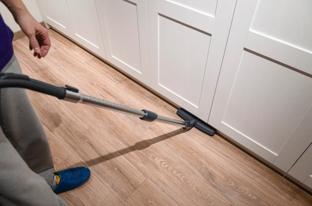 How to Survive a Kitchen Remodel - A picture of a person vacuuming a kitchen floor.