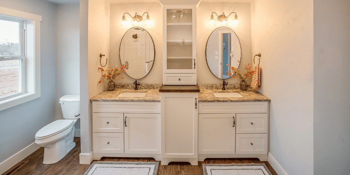 A bathroom with a modern Jack and Jill vanity incorporating oval mirrors and bright, vintage style lighting 