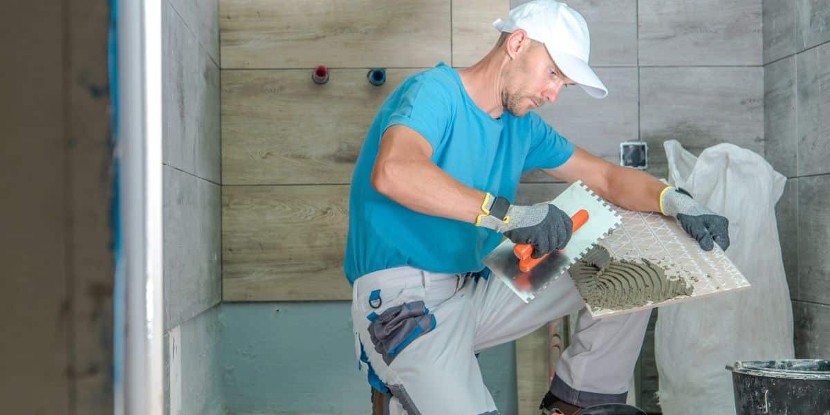 man laying tile in a bathroom