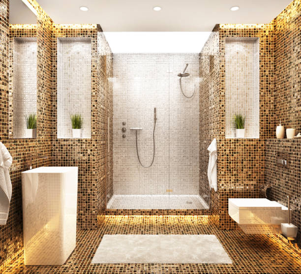 Modern bathroom with gold and brown mosaic tiles, a walk-in shower with a glass door, rainfall showerhead, towels, wall-mounted toilet, rectangular sink, and decorative plants on shelves.